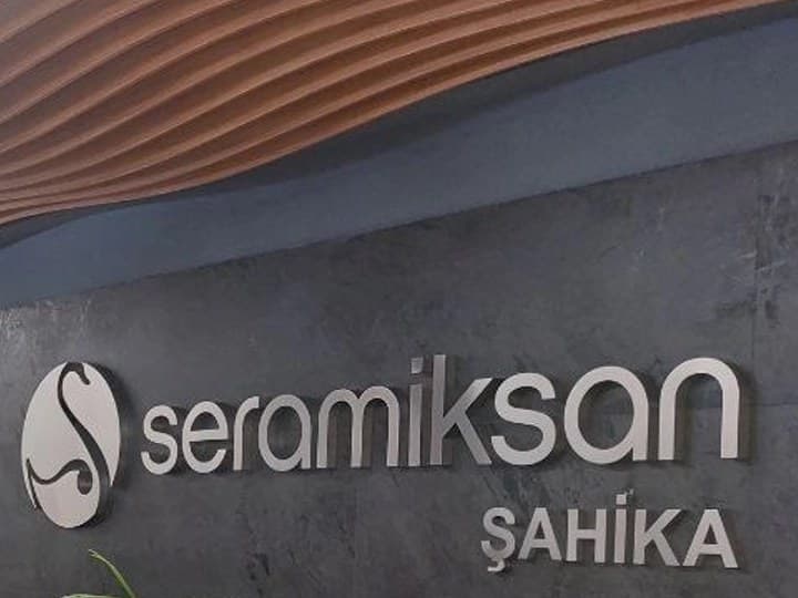Showroom girişindeki dalgalı ahşap tavan ve üzerinde seramiksan ŞAHİKA yazan mermer karşılama duvarı
